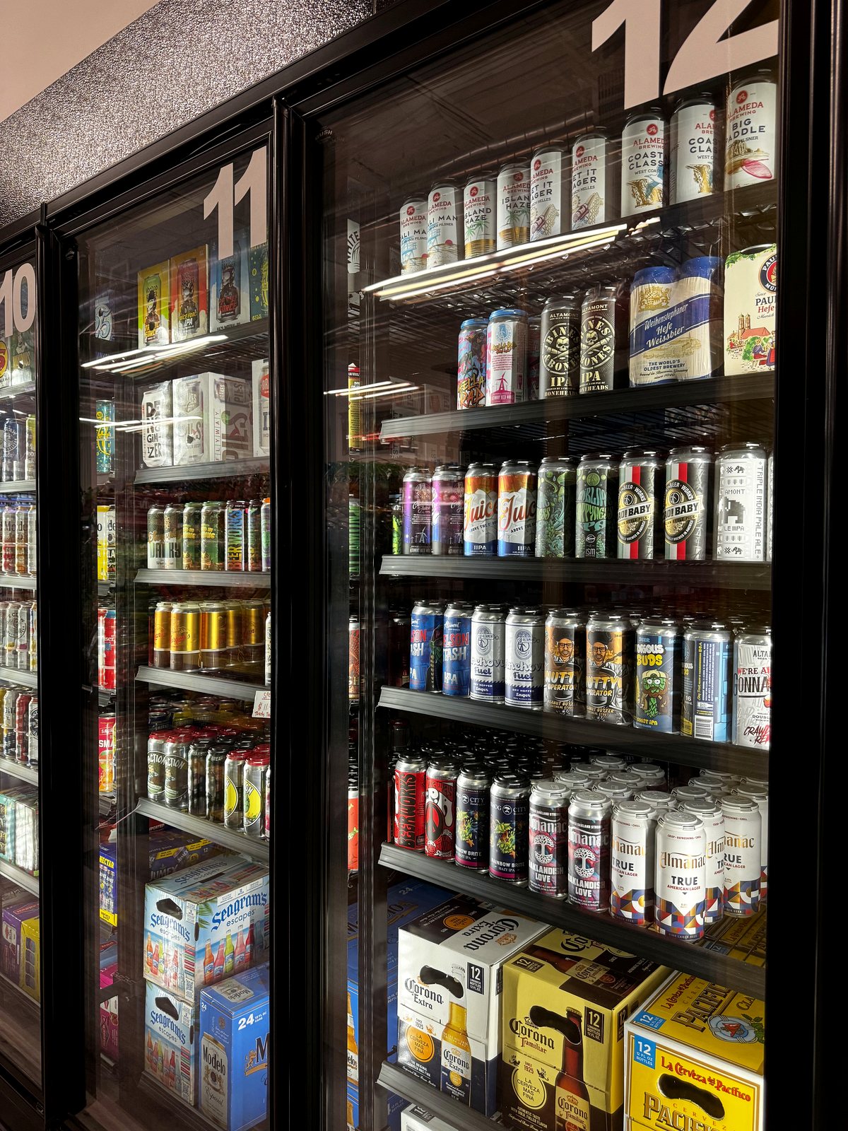 The refrigerated beer wall at Marina Wine & Spirits, stocked with cans and bottles from local East Bay breweries alongside imports.